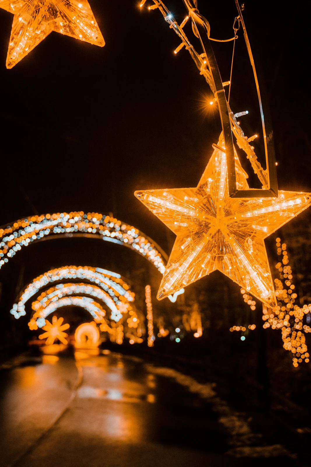 Holiday light installations reflected on a wet walkway